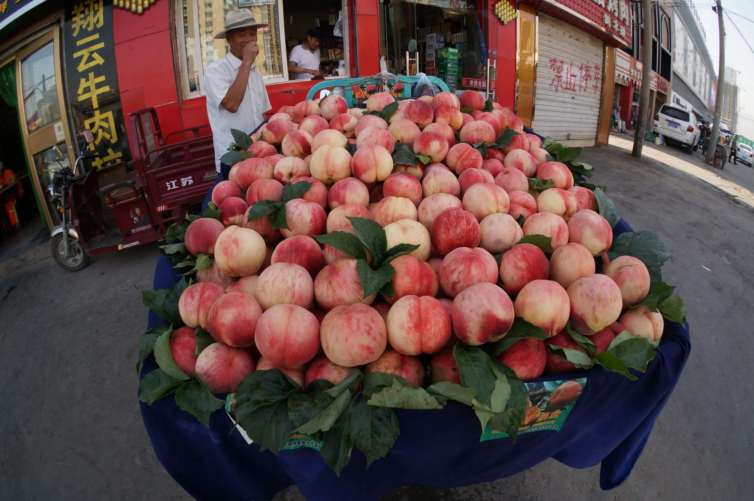 西驛国際青年旅舎のある路地前で桃を売っている露店商